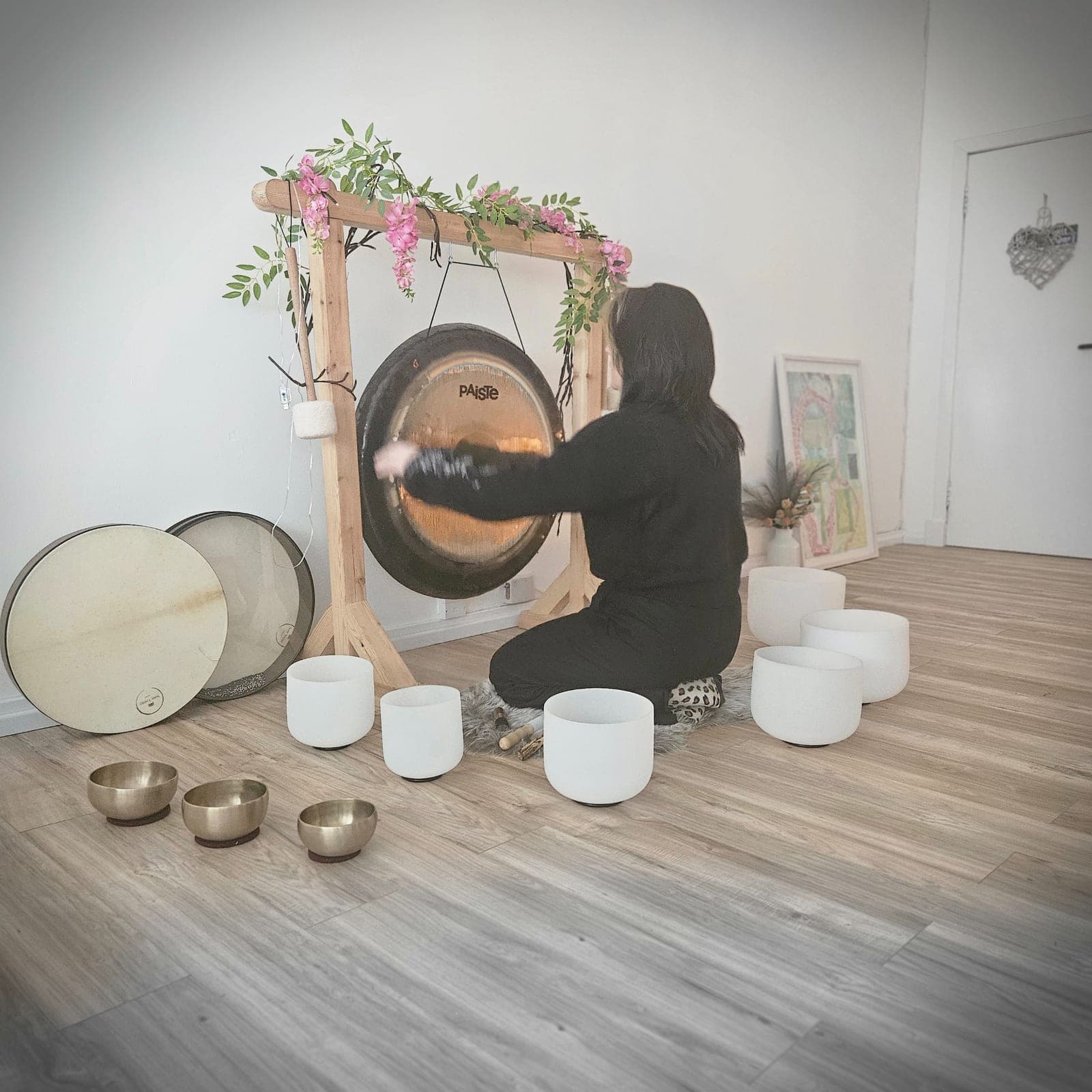 Jodi playing the gong, surrounded by singing bowls and drums, at The Reset Room Glasgow