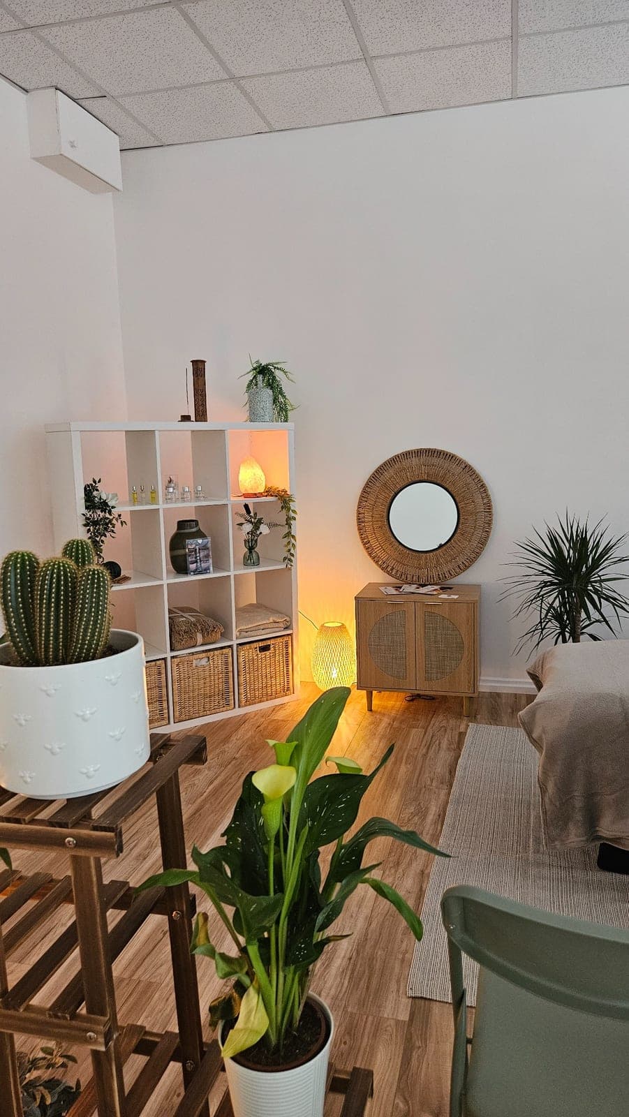 Plants, round mirror and soft lighting in the treatment room at The Reset Room Glasgow